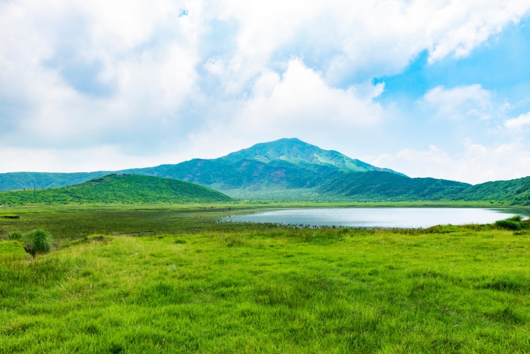 Scenic view of Aso-Kujū National Park, featuring the expansive caldera of Mount Aso, diverse landscapes, and hiking trails during a Travellers Autobarn campervan road trip.