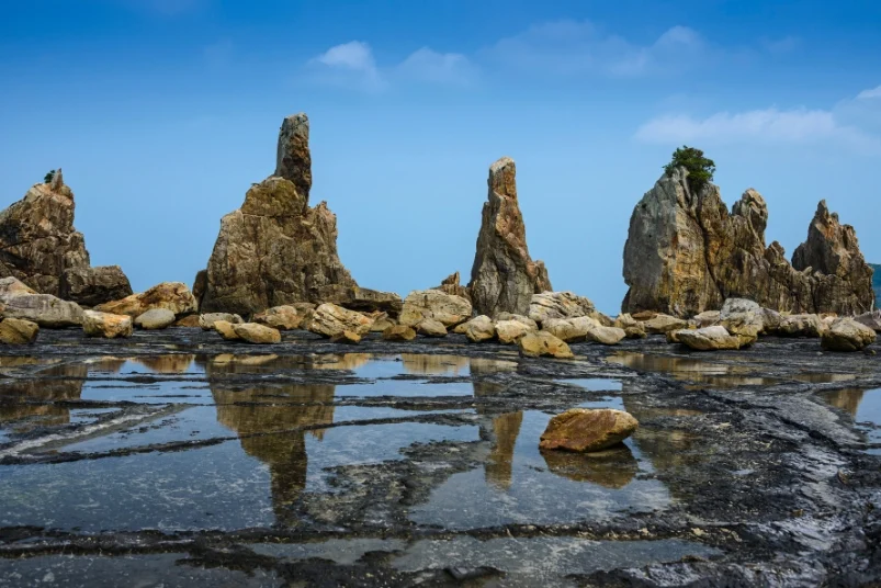 The unique Hashikui-iwa rock formations reflecting in shallow tidal pools.