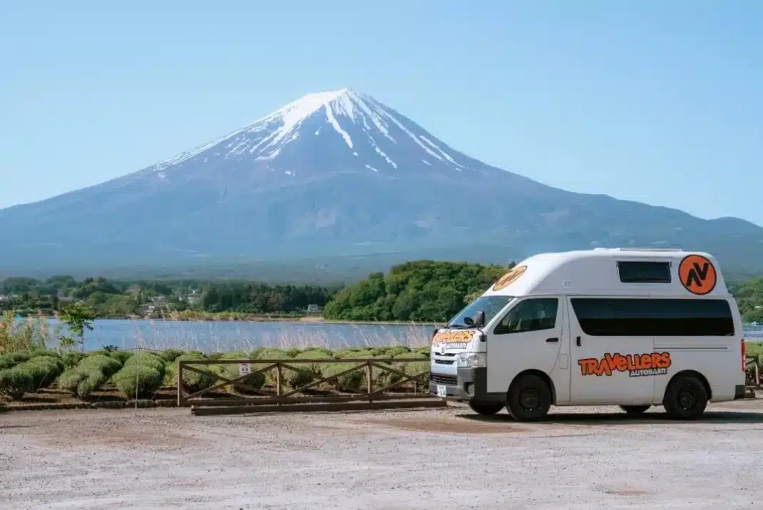 White Travellers Autobarn campervan parked in Yamanashi with iconic Mt. Fuji and lake Kawaguchi in the background