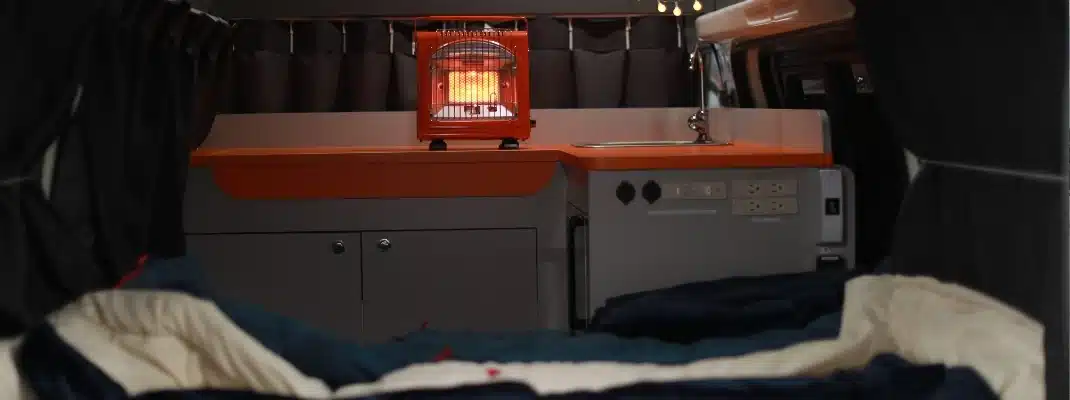 Interior of a campervan showing a kitchenette counter with a small portable heater turned on