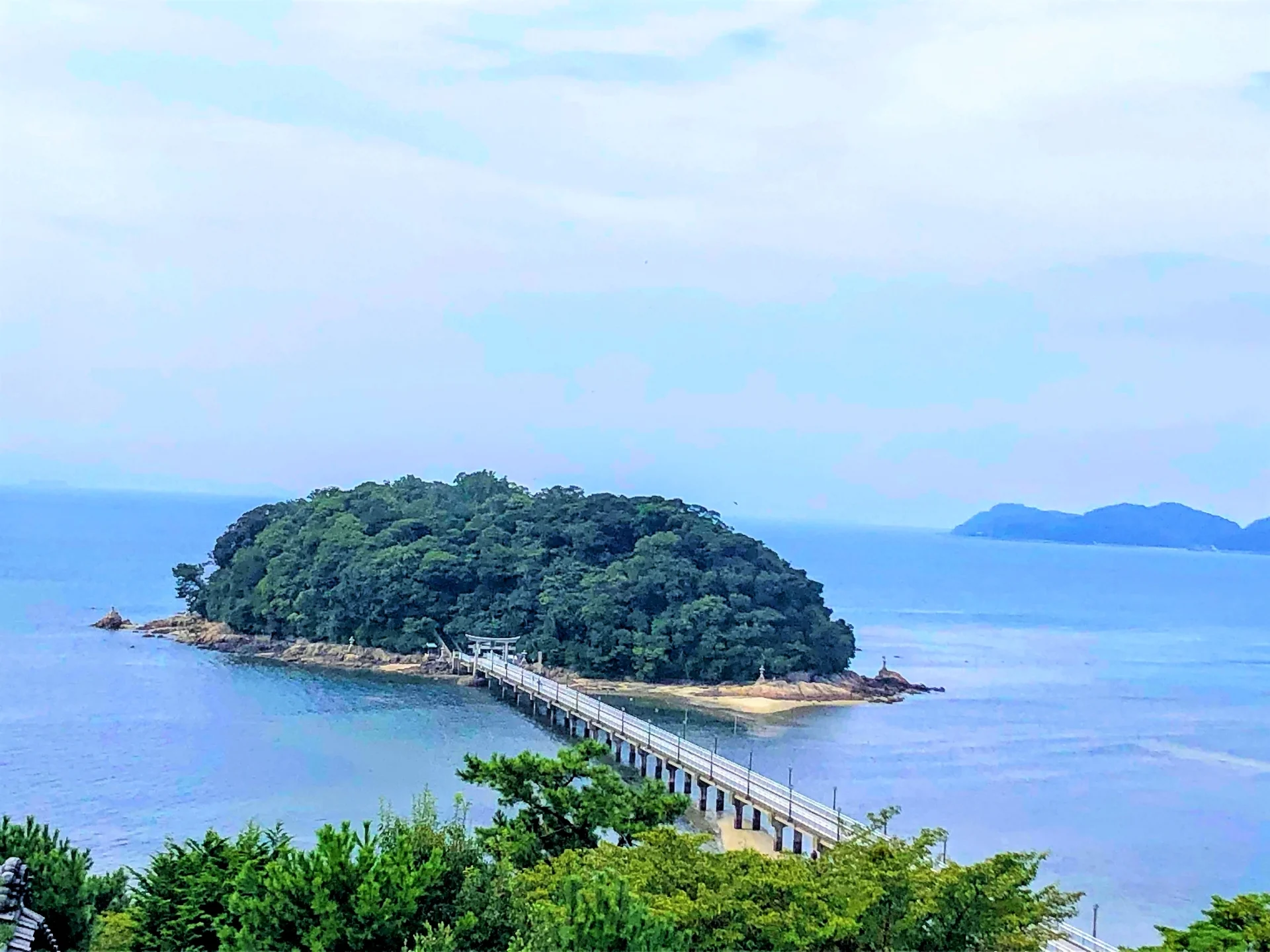 High-angle view of Takeshima Island in Gamagori, connected to the mainland by a long pedestrian bridge across the blue sea.